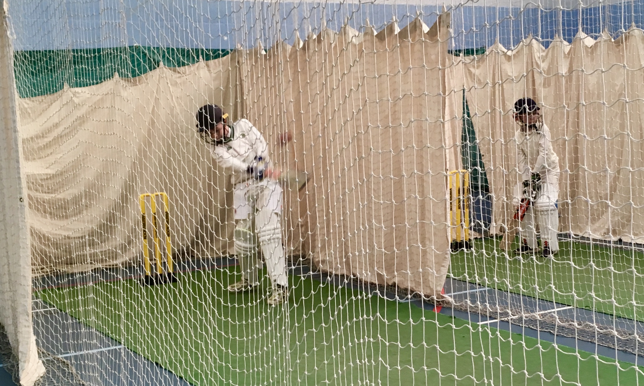 Young cricketers hitting the ball in the nets