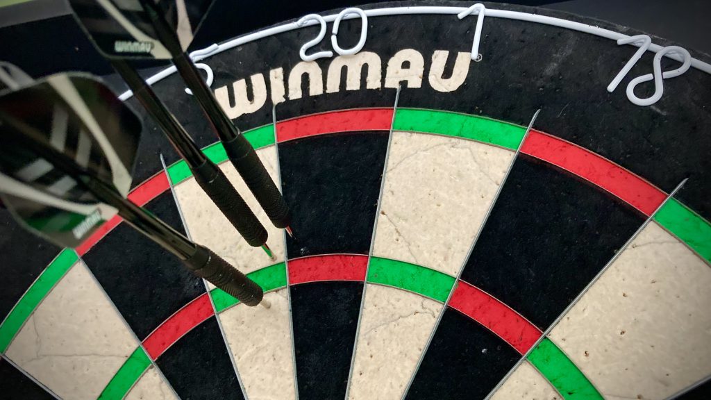 A dartboard with two darts in the 5 and one dart in the 20. All three are near the treble 20 but their combined score is just 30.